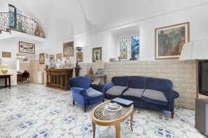 A spacious living room with a blue sofa, two armchairs, a coffee table, and a fireplace.