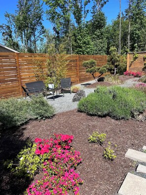 A garden with a wooden fence, outdoor furniture, and various plants. - Sustainable Garden Suite Retreat - Modern, serene & peaceful oasis (Nanaimo)