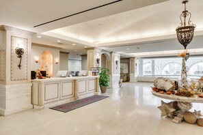 Eine geräumige Lobby mit Empfangstresen, einem großen Kronleuchter und einem dekorativen Mittelstück.