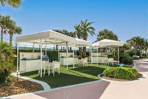 Ein Außenbereich mit Terrasse, weißen Markisen, einer Grillstation und Sitzgelegenheiten.