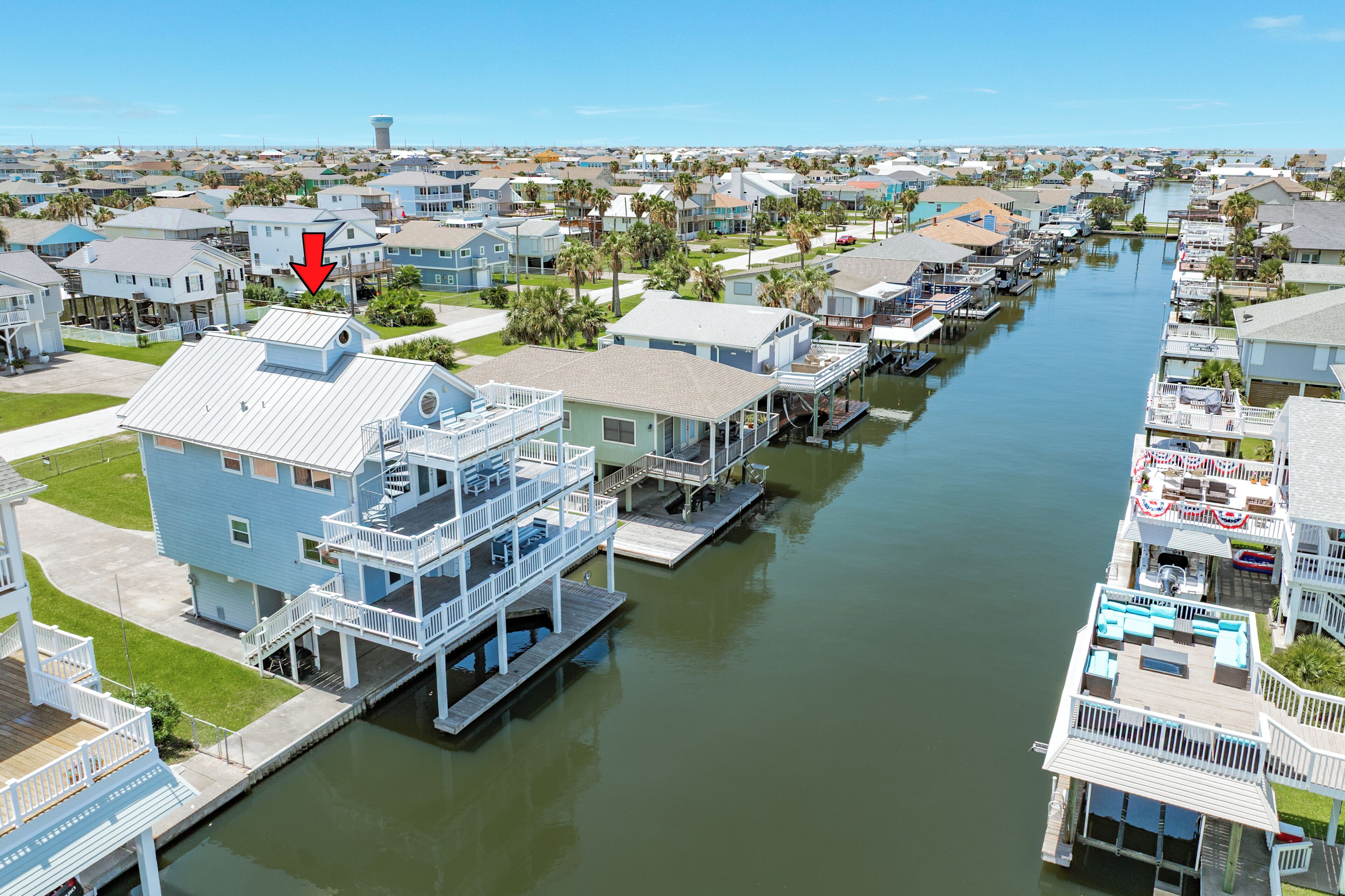 A waterfront residential area with houses connected by a canal, featuring elevated walkways and docks.