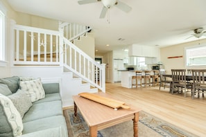 Un vaste espace de vie comprenant un escalier, un coin repas avec des chaises en bois et une cuisine à l’arrière-plan.