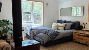 A bedroom with a bed, a wooden dresser, a potted plant, a heater, and a ceiling fan.