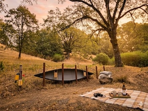 A picnic setup with a blanket, a bottle, binoculars, and a small boat in a natural setting.