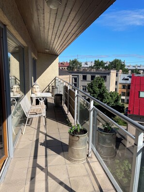 Ein Balkon mit Metallgeländer, Blumentöpfen, einem Metallstuhl und einem Tisch.