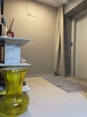 Ein Zimmer mit einer Marmorablage, einer gelben Glasvase, einem gemusterten Teppich und einer Tür mit Zahlenschloss.