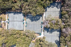 Eine Luftaufnahme eines Tennisplatzkomplexes, umgeben von dichtem Baumbestand.