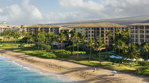 Ein Strandhotel mit mehreren Gebäuden, Palmen und einem Sandstrand.