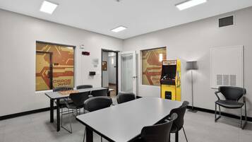 A conference room with a chessboard, chairs, tables, a clock, and a vending machine.