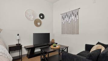 A modern living room with a flat-screen TV, a coffee table, and a couch.