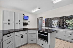 A modern kitchen with grey cabinets, a black countertop, and a microwave. - Modern King Suite - Steps from UAT and near ASU (Tempe)