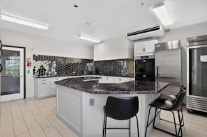 A modern kitchen with a central island, white cabinetry, a black hexagonal backsplash, stainless steel appliances, and a black bar stool. - Modern King Suite - Steps from UAT and near ASU (Tempe)