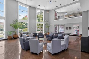 A spacious lobby with modern furniture, large windows, and a high ceiling. - Modern King Suite - Steps from UAT and near ASU (Tempe)