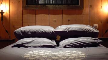 A bed with a heart-shaped lace design, wooden walls, and two wall-mounted lamps.