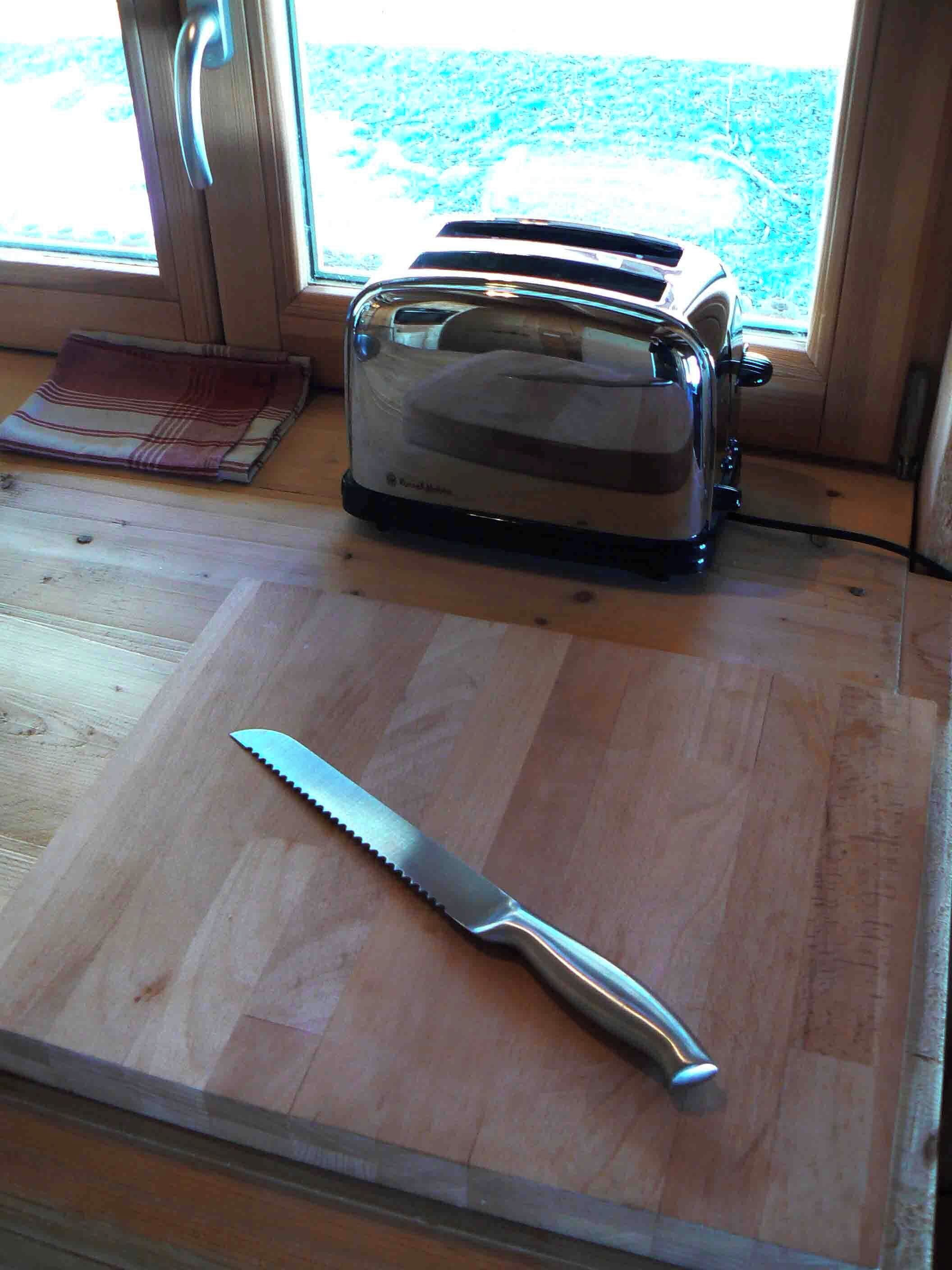 Una cocina con un tostador en la encimera, una tabla de cortar y un cuchillo.