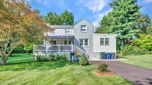 A two-story house with a front porch, a garage, and a well-maintained lawn. - Family Retreat with Pool & Playground (Roslyn)