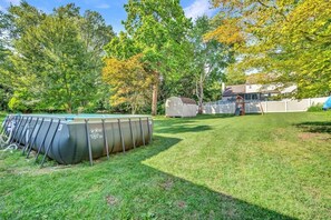 A backyard with a swimming pool, a shed, and a house.