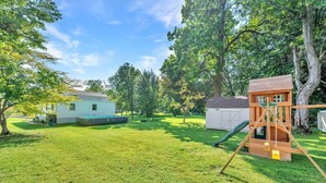 A backyard with a wooden play structure, a small shed, and a house. - Family Retreat with Pool & Playground (Roslyn)