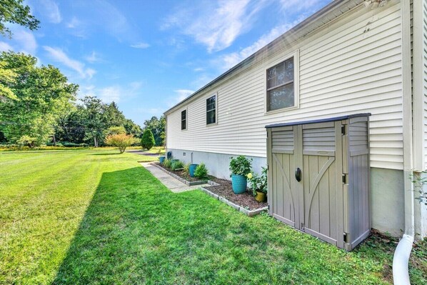 A single-story house with a garage, a well-maintained lawn, and a variety of potted plants.