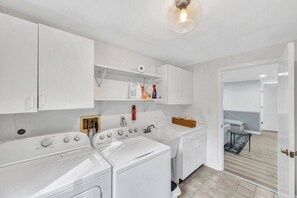 A modern kitchen with white appliances, a built-in oven, and a countertop with a coffee machine.