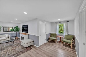 Ein modernes Wohnzimmer mit einer Couch, einem Couchtisch, einem Fernseher und einem kleinen Tisch mit Stühlen.