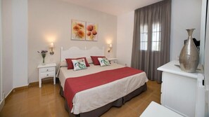 A hotel room with a bed, nightstands, a dresser, and a vase. - Aptos Leo San Bruno I Ii (Ayamonte)