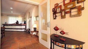 Un hall de hotel con mostrador de recepción, zona de estar y una pared decorativa.