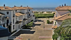 Zona residencial costera con edificios blancos, cielo despejado y vista a la playa.