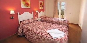 Un dormitorio con dos camas, una ventana con cortinas y lámparas fijadas a la pared.