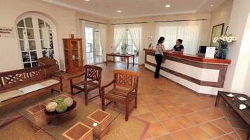 Una hall d'albergo con reception, arredi in legno e un'indicazione per il ristorante.