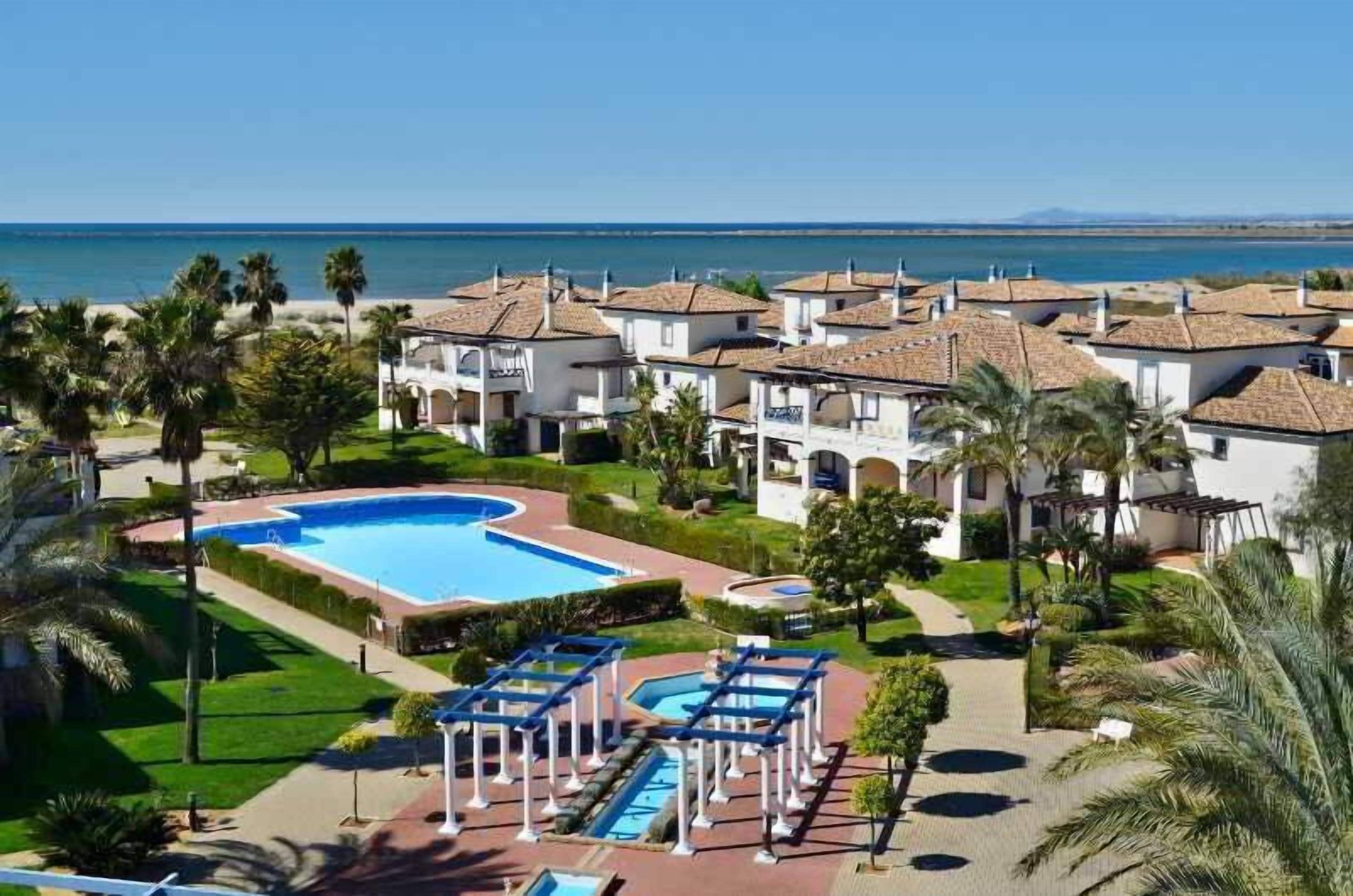 Een resort met een zwembad, meerdere gebouwen en uitzicht op zee.