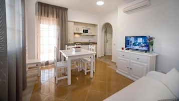 Un espacio habitable compacto con kitchenette, comedor y zona de estar.
