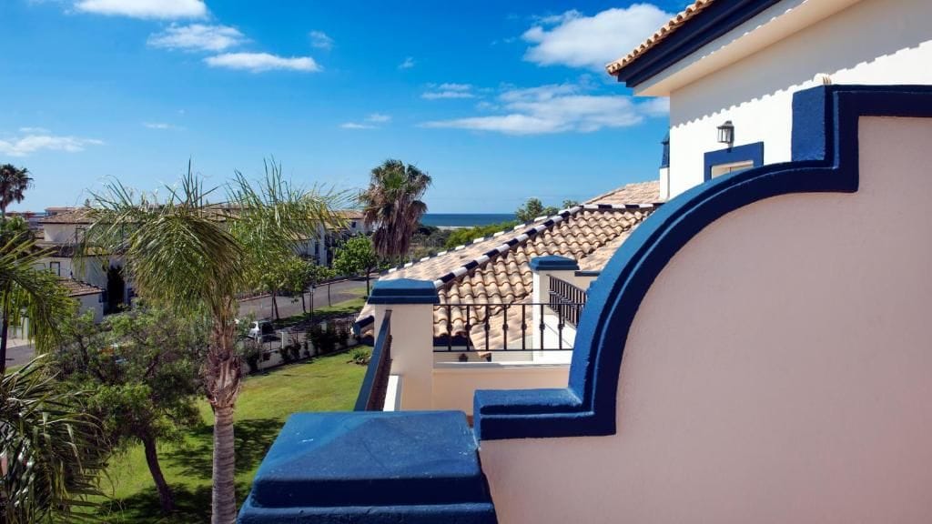 Un edificio con un balcón curvo que da a un jardín y vistas al mar.