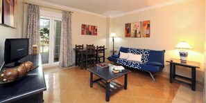 A living room with a sofa, coffee table, TV, and a dining area with chairs and a table. - Aptos Leo San Bruno I Ii (Ayamonte)