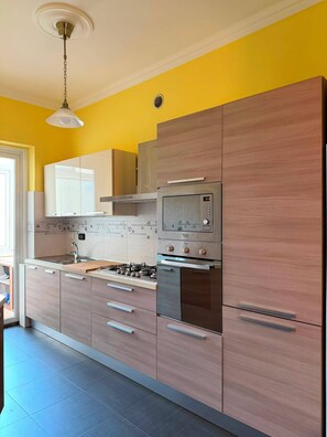 Eine moderne Küche mit Holzschränken, Edelstahlgeräten und einer gefliesten Spritzschutzwand.