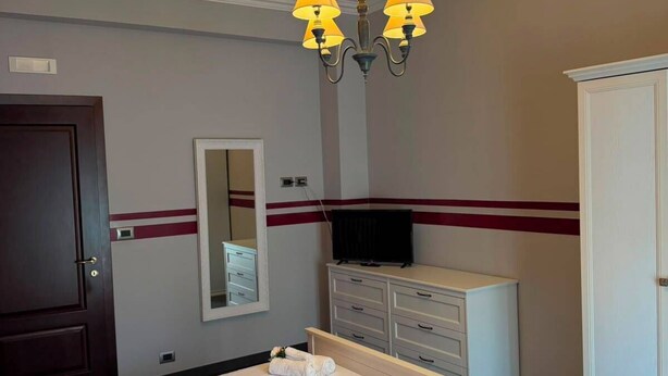 A hotel room with a bed, a wardrobe, a television, and a mirror. - Apartment located in a prime location in Ostia Lido (Lido di Ostia)