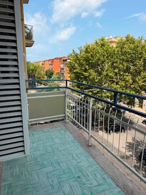 Ein Balkon mit Blick auf einen Baum und Gebäude.