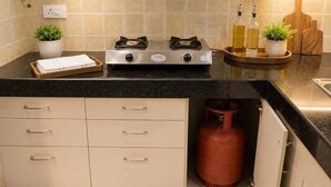 A kitchen with a gas stove, cabinets, a countertop, and a gas cylinder.