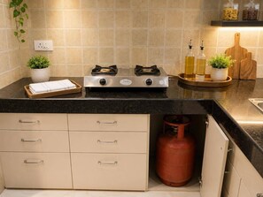 A kitchen with a gas stove, cabinets, a countertop, and a gas cylinder. - 3BHK Luxury Villa (Thane)