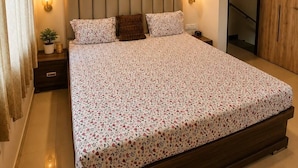 A bedroom with a bed, a ceiling fan, a wall-mounted light, and a door.