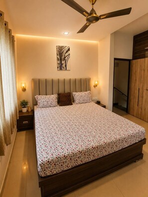 A bedroom with a bed, a ceiling fan, a wall-mounted light, and a door. - 3BHK Luxury Villa (Thane)