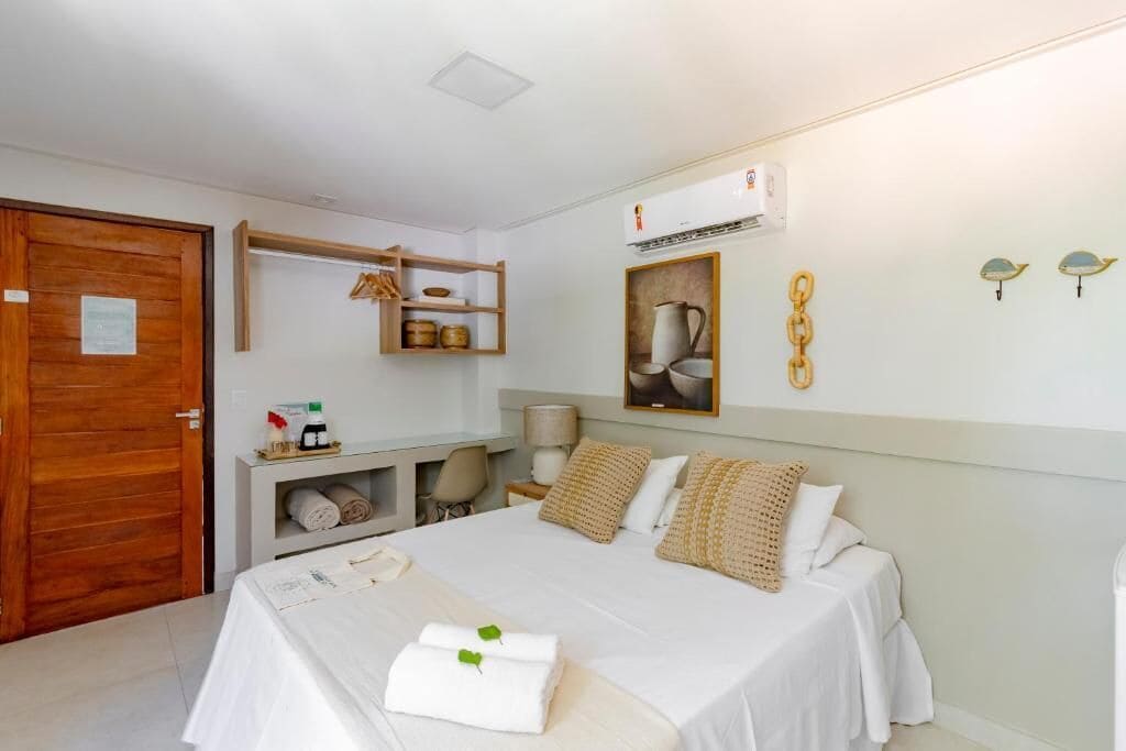 Habitación de hotel con cama, escritorio, silla, armario y aire acondicionado de pared.