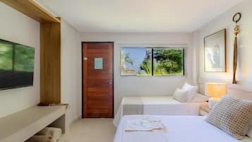 A hotel room with a bed, a desk, a chair, a window with a view of greenery, and a door.