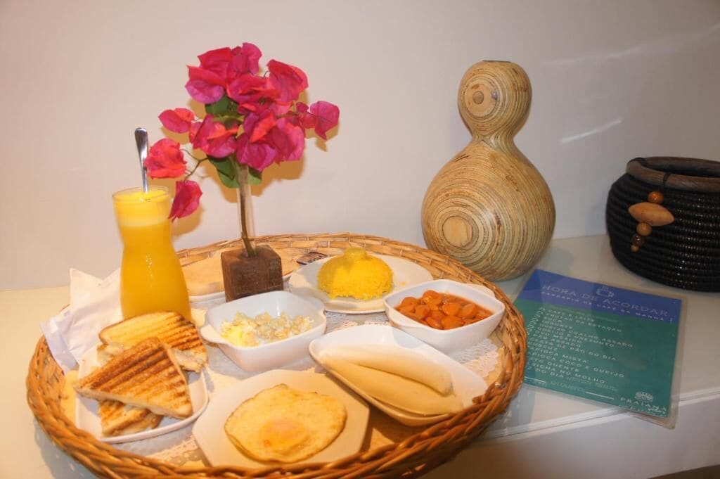 Bandeja de desayuno con tostadas, huevos revueltos, un frutero y una vela.