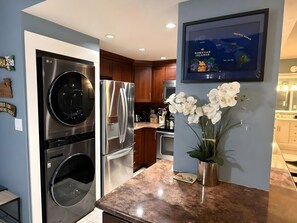 A modern kitchen with stainless steel appliances, wooden cabinets, and a marble countertop. - Sunny 4BR, 2 Condos for 12 in Lahaina, Hawaii! (Lahaina)