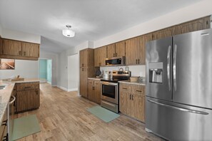 Eine moderne Küche mit Holzschränken, Edelstahlgeräten und einer Arbeitsplatte aus Granit.