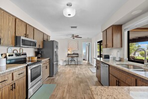 A modern kitchen with wooden cabinets, stainless steel appliances, and a view to the outside. - Seaside Villa Paradise Point - large heated pool, wide canal, south facing, (Cape Coral)