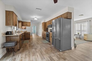 A modern kitchen with wooden cabinets, stainless steel appliances, and a view to the living area. - Seaside Villa Paradise Point - large heated pool, wide canal, south facing, (Cape Coral)