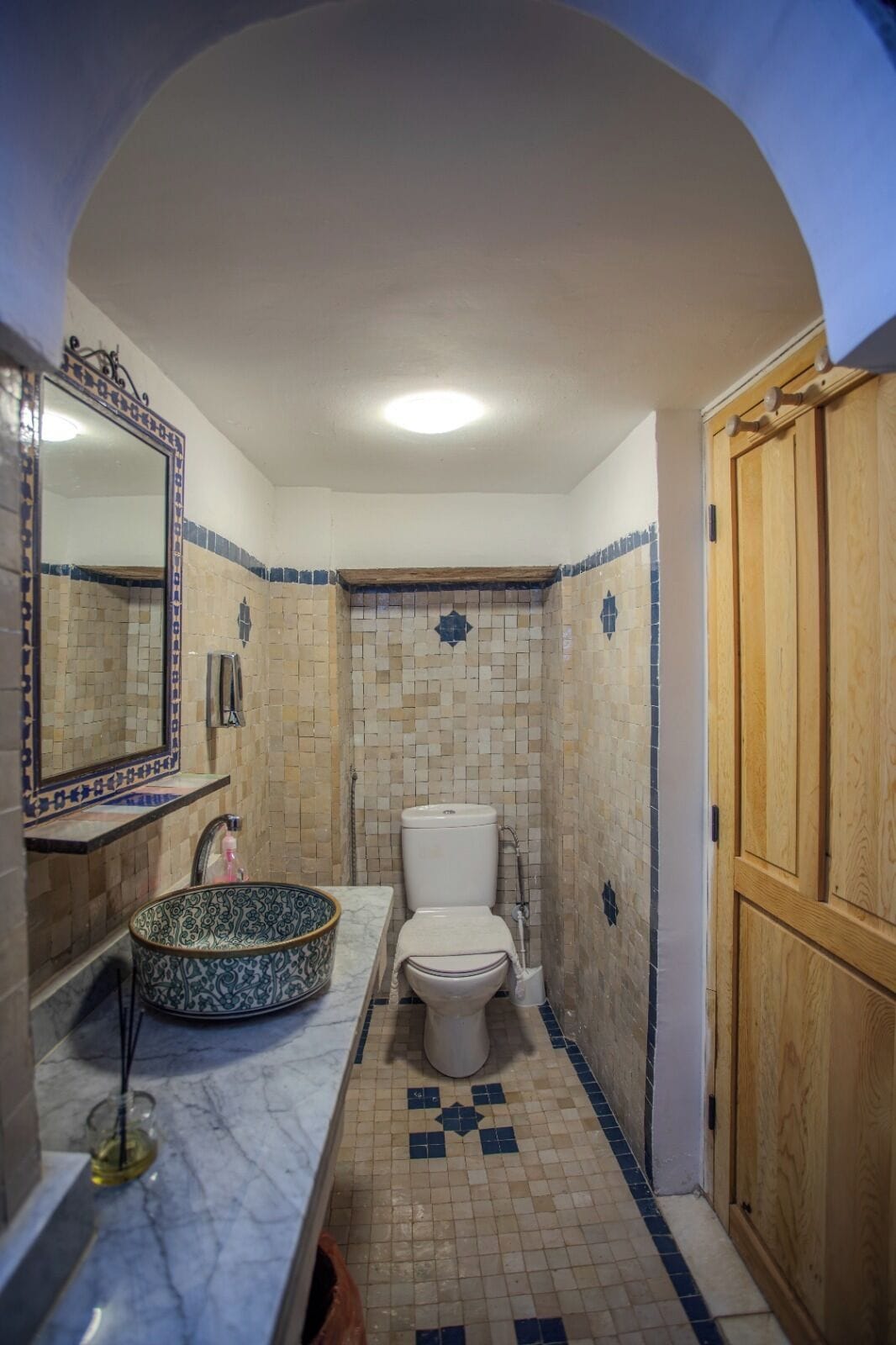 A bathroom with a marble sink, a toilet, and a wooden door.
