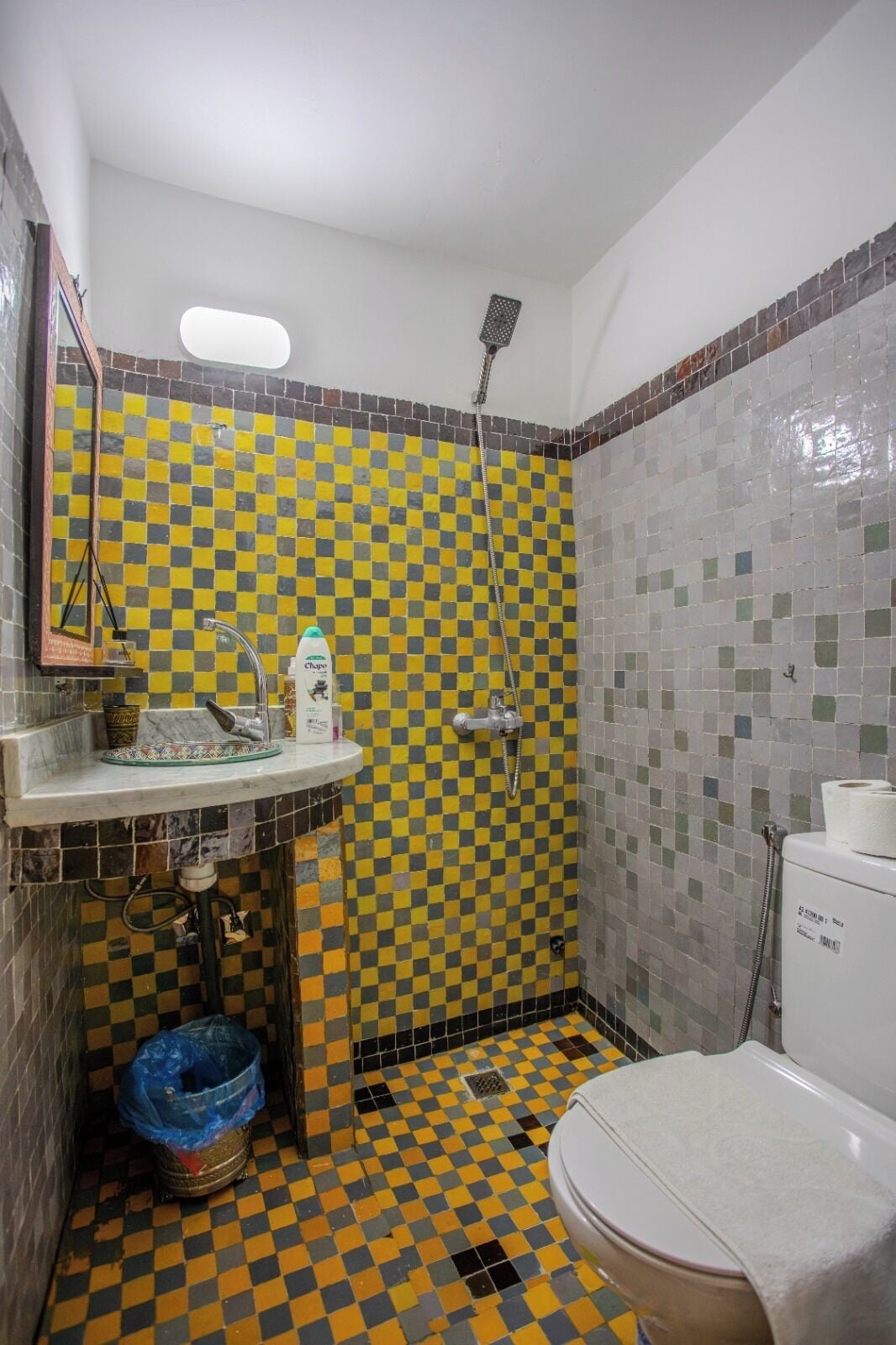 Un baño con piso a cuadros, lavamanos, inodoro y ducha.